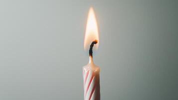 A single lit candle with a red and white striped candle photo