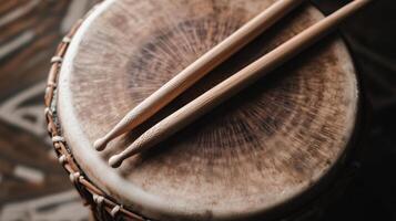 A drum and two wooden sticks on a wooden surface photo