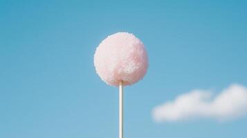 A pink lollipop on a stick against a blue sky photo