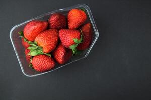 Strawberries in a bowl stand on a black table. Top view. photo