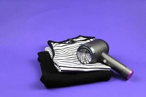 On a purple background are folded basic T-shirts. The lint machine means clean clothes without unnecessary waste. photo