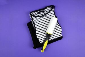 Concept of care and concern for clothes.Clothing roller lies on a purple background. Top view. photo