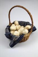 Champignons in a wicker basket, lying on a woven towel on a white background photo