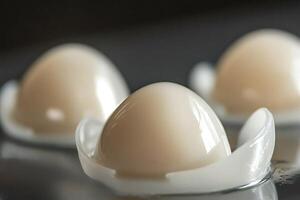 Modern artificial breast implants resting on reflective surface photo