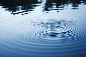 Water drop creating concentric ripples on calm surface photo