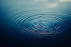 Water droplet creating concentric ripples on calm surface photo