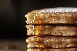 Stack of pancakes dripping with maple syrup and icing sugar photo