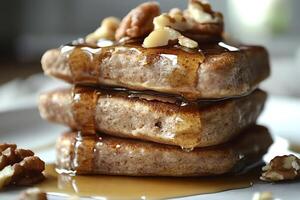 Stack of pancakes dripping with syrup and topped with walnuts and pecans photo