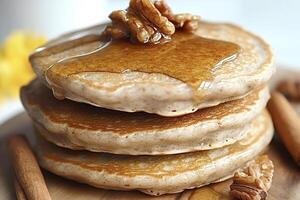 Stack of pancakes dripping with syrup and topped with pecans photo