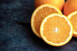 Sliced and whole oranges resting on dark stone surface photo