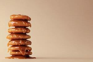 Stack of cookies covered in dripping caramel on a beige background photo