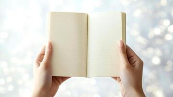 Woman holding open notebook with empty pages on blurred background photo