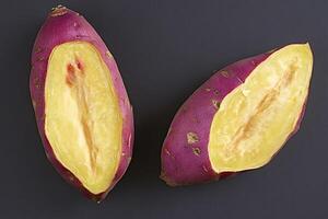 Two halves of cooked sweet potato resting on dark surface photo