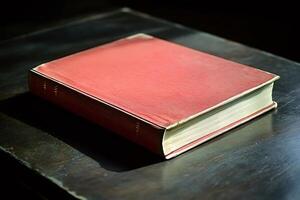 Red hardcover book lying on dark wooden table photo