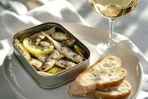 Sprats in olive oil served with lemon, parsley, bread and white wine photo