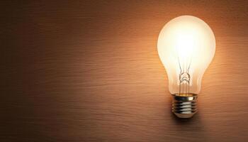 Illuminated Light Bulb Against Wood Background with Copyspace for Creative Ideas photo