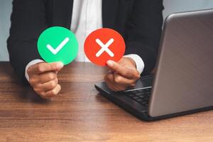 Hand holding two green and red paper with a checkmark and cross photo