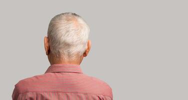 Back view of a senior man with short gray hair while standing on a gray background. photo
