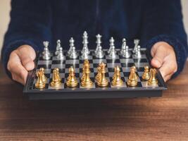 Chessboard in hands prepares to play a chess game while sitting at the table photo