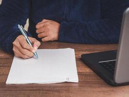 Close-up of a businessman in a sweater signing a lease contract or agreement while sitting at the table. photo