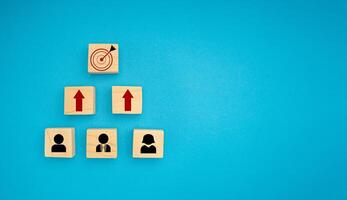 Wooden blocks with black people and red arrow icons pointing to the dartboard icon on a blue background photo