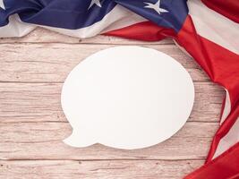 Top view of the American flag with blank white a speech bubble over a wooden table. Space for text. photo
