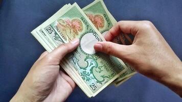 Top view of a man hand counting several old rupiah banknotes of Rp 25 rupiah denomination, isolated on a black background photo