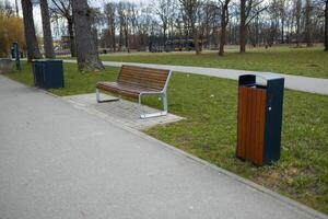 Park Bench with Trash Bins along a Path in a Public Park photo