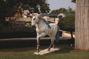 Majestic and Beautiful Unicorn Sculpture Displayed in a Lush and Enchanting Garden Setting photo