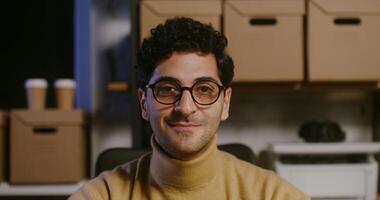 A man in glasses sitting at a desk in front of a computer photo