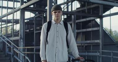 A man with a backpack and a hat standing in front of a building photo