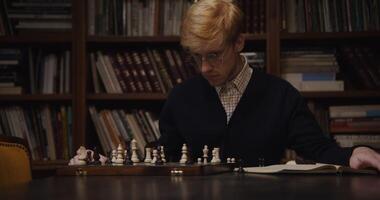 A man in glasses playing chess on a table photo