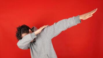 Happy man in casual making dab arms gesture on blank red studio background, funny white guy dabbing moving in internet meme pose celebrating victory having fun, dance school triumph concept. photo
