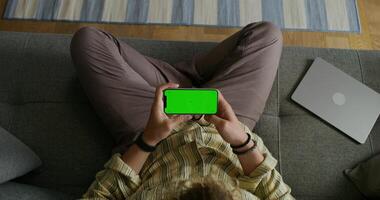 Man using laptop and tablet with green screen in sofa photo