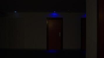 Blue lights casting soft, mysterious glow along dark hotel corridor, creating eerie atmosphere of suspense through shadowy architectural lines and dim illumination video