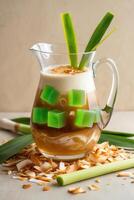 A refreshing beverage in a pitcher, featuring layers of coffee, coconut, and green jelly cubes. photo