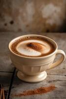 A creamy coffee topped with cinnamon, served in a decorative cup on a rustic surface. photo