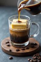 A glass of coffee with a butter cube, showcasing a unique drink preparation. photo