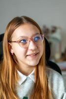 A girl with glasses and a grey sweater sitting in front of a computer photo