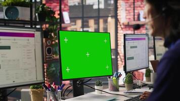 Call center worker solving customers issues using green screen PC. Customer support staff member in front of chroma key computer display using headset to talk with clients, camera A video