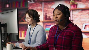 Call center agent in noisy office asking coworker to lower voice while providing guidance to customers. Customer center employee irked by loud colleague during conversation with client, camera A video
