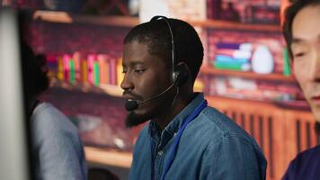 Team of multiethnic call center agents in workplace helping customers. Multiracial workers in diverse customer center assisting clients needing help resetting password, camera A video