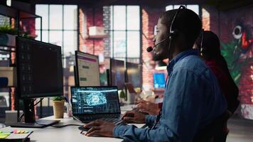 Call center worker in office using AI chatbot to answer customer questions. Man doing customer service job using artificial intelligence, generating automated responses providing solutions, camera B video