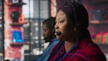 Call center agent listening to customer needs, providing step by step guidance. Customer center worker manages incoming and outgoing calls, walking clients through technical solutions, camera A video