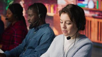 Customer support workplace coworkers managing incoming and outgoing calls. Teamworking call center agents in front of PC in office using headset mic to answer customers questions, camera A video