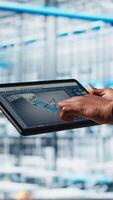 Vertical Photovoltaic smart factory specialist uses tablet to design production lines in CAD software. Industry 4.0 solar panels plant employee uses device to optimize floor layouts, camera A close up video