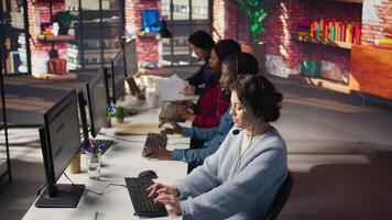 Customer support workplace coworkers managing incoming and outgoing calls. Teamworking call center agents in front of PC in office using headset mic to answer customers questions, camera B video