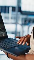 Vertical Solar panels plant worker tracking energy production through IoT sensors on notebook. Engineer in smart photovoltaics factory looking at system performance metrics on laptop, camera A close up video