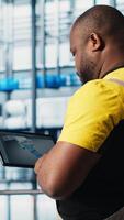 Vertical Industry 4.0 industrial plant expert designs new robotic machines using CAD program on tablet. Africna american man in smart factory using device to do tooling for automation equipment, camera A video