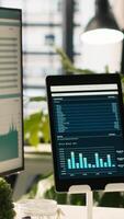 Vertical Modern workspace with key performance indicators data on display in bright office environment with potted plants. PC and tablet on desk with accounting figures displayed on screen, close up shot video